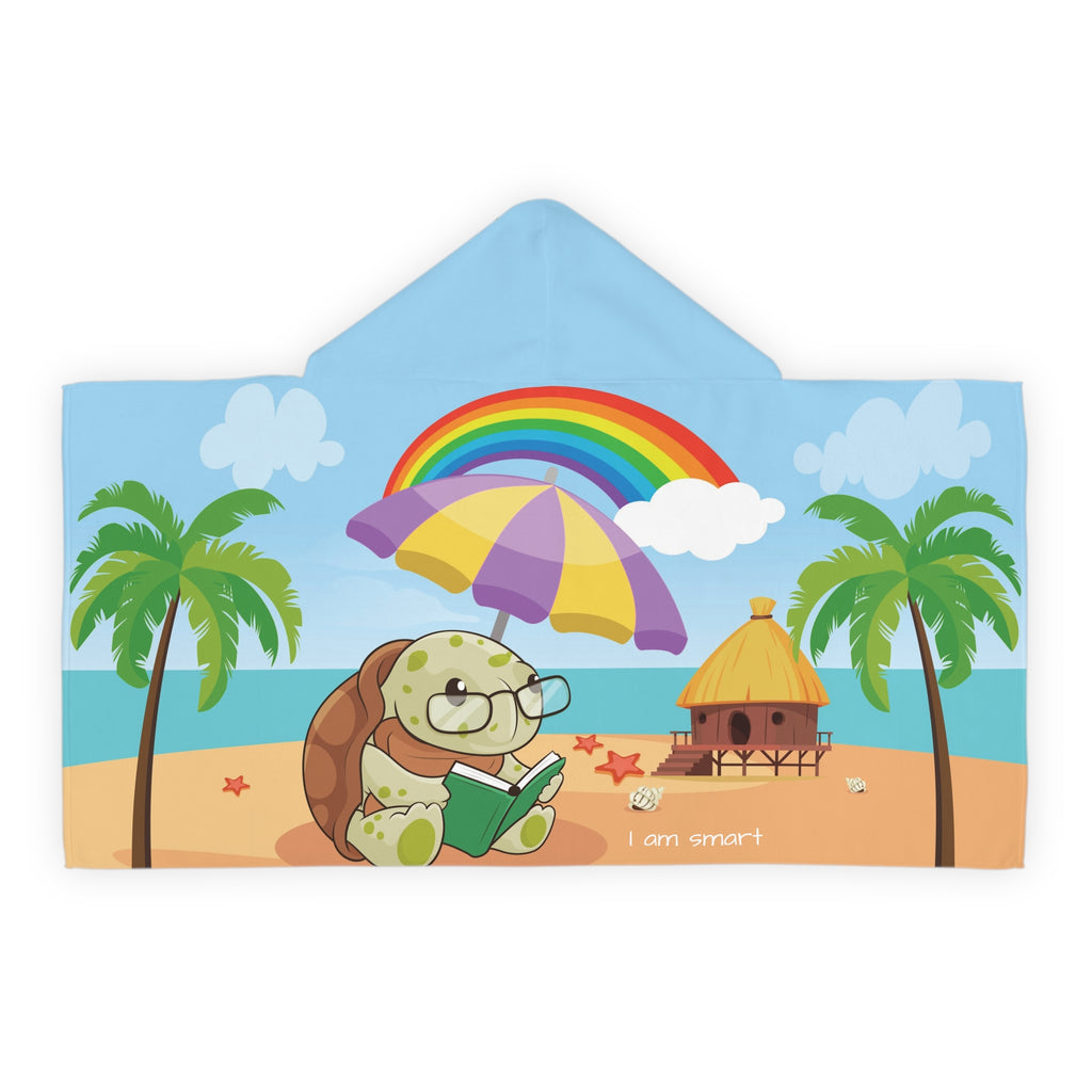 Back-view of a hooded towel with a scene of a turtle reading a book under an umbrella on the beach, a rainbow in the background, and the phrase "I am smart" along the bottom.