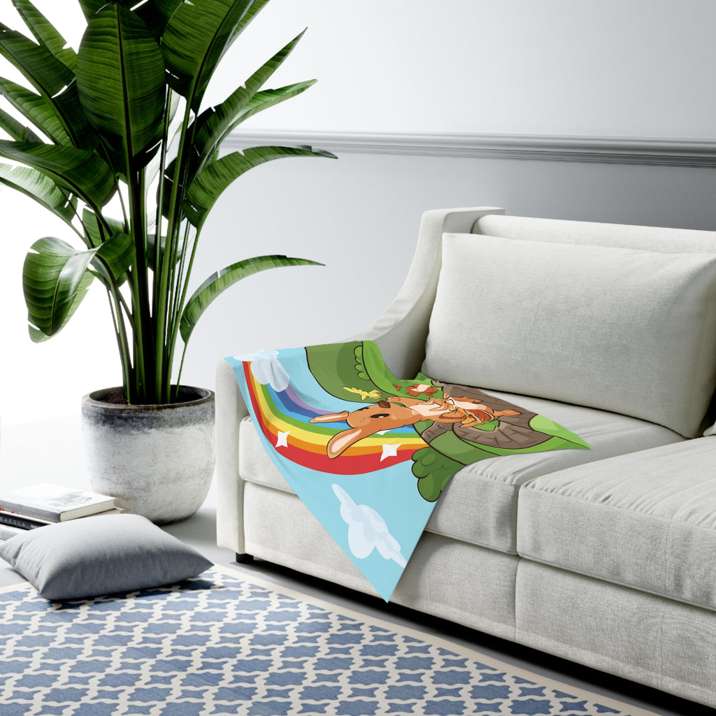 Full-color swaddle blanket with a kangaroo walking along a path through rolling hills with a rainbow in the background. The blanket is draped over the armrest of a couch.