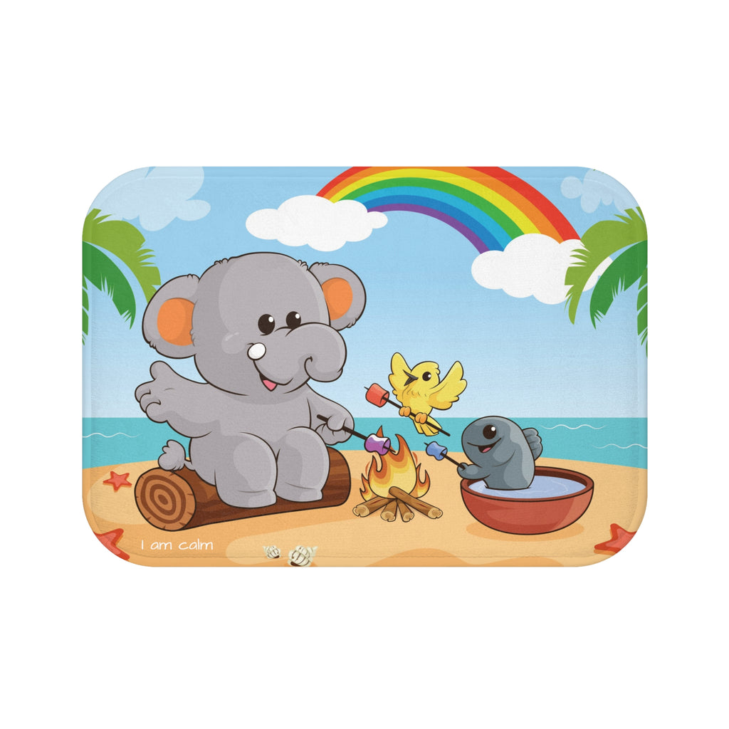 A 24 by 17 inch bath mat that has a scene of an elephant having a bonfire with a bird and fish on the beach, a rainbow in the background, and the phrase "I am calm" along the bottom.