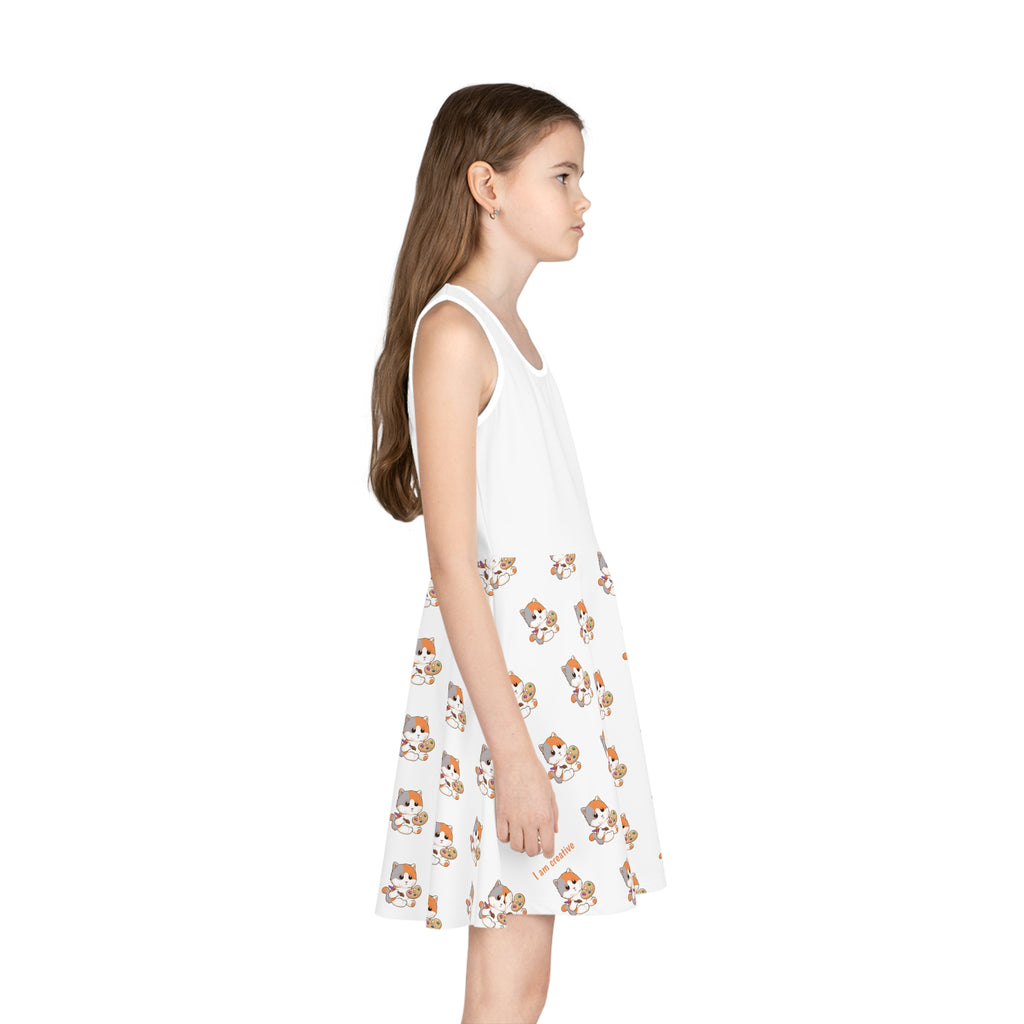 Right side-view of a girl wearing a sleeveless white dress with a white top and a repeating pattern of a cat on the skirt.