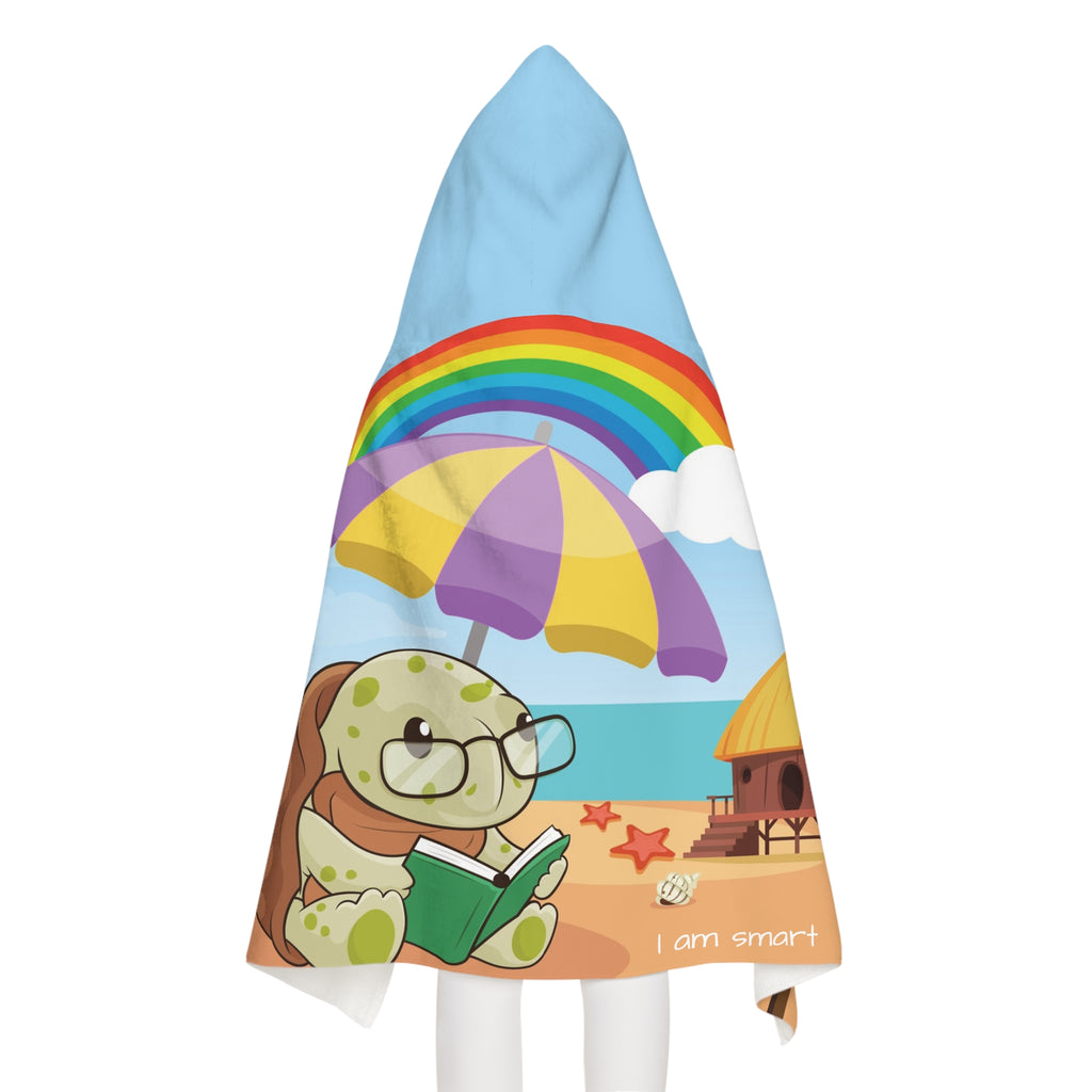 Back-view of a girl wearing a hooded towel. The towel has a scene of a turtle reading a book under an umbrella on the beach, a rainbow in the background, and the phrase "I am smart" along the bottom.
