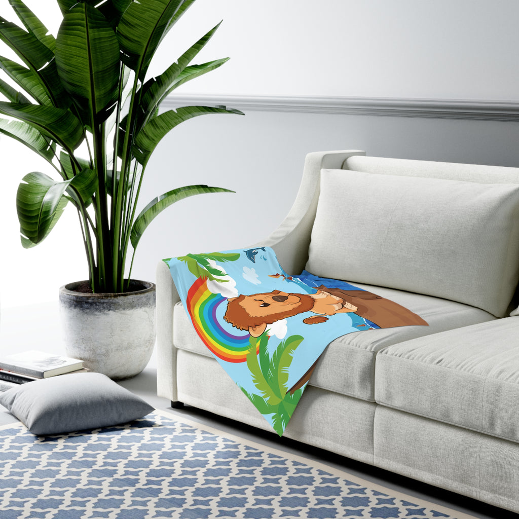 Full-color swaddle blanket with a lion standing on a cliff over the ocean with a rainbow in the background. The blanket is draped over the armrest of a couch.
