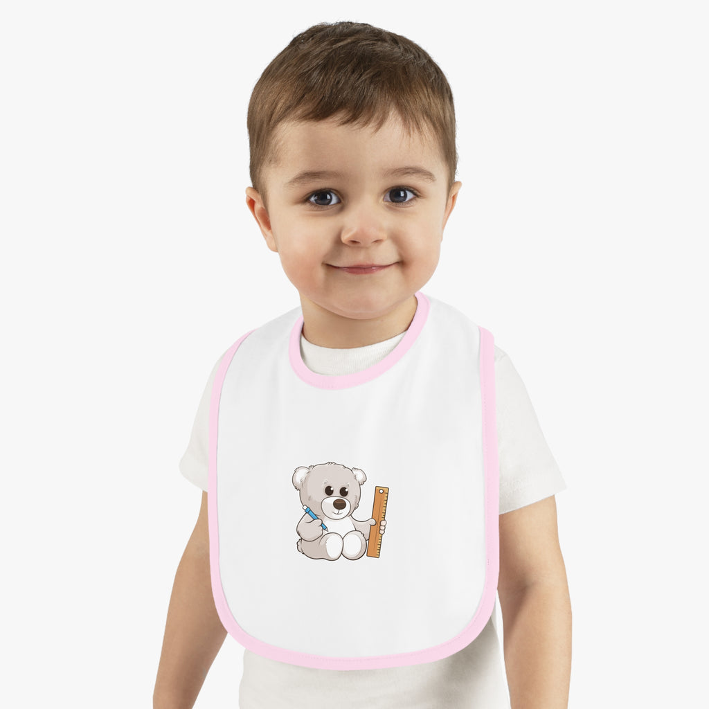 A little boy wearing a white baby bib with light pink trim and a small picture of a bear.