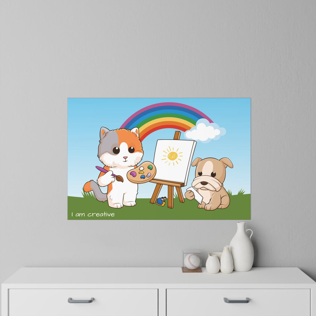 A 36 by 24 inch wall decal on a grey wall above a dresser. The wall decal has a scene of a cat painting on a canvas next to a dog, a rainbow in the background, and the phrase "I am creative" along the bottom.