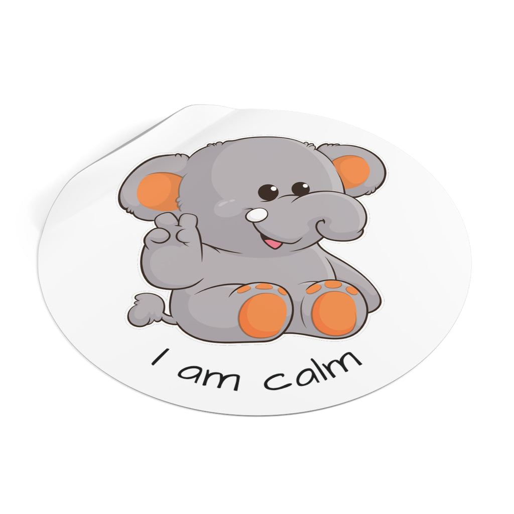 A 4 by 4 inch round white vinyl sticker with a picture of an elephant that says I am calm. The edge of the sticker is curled up.