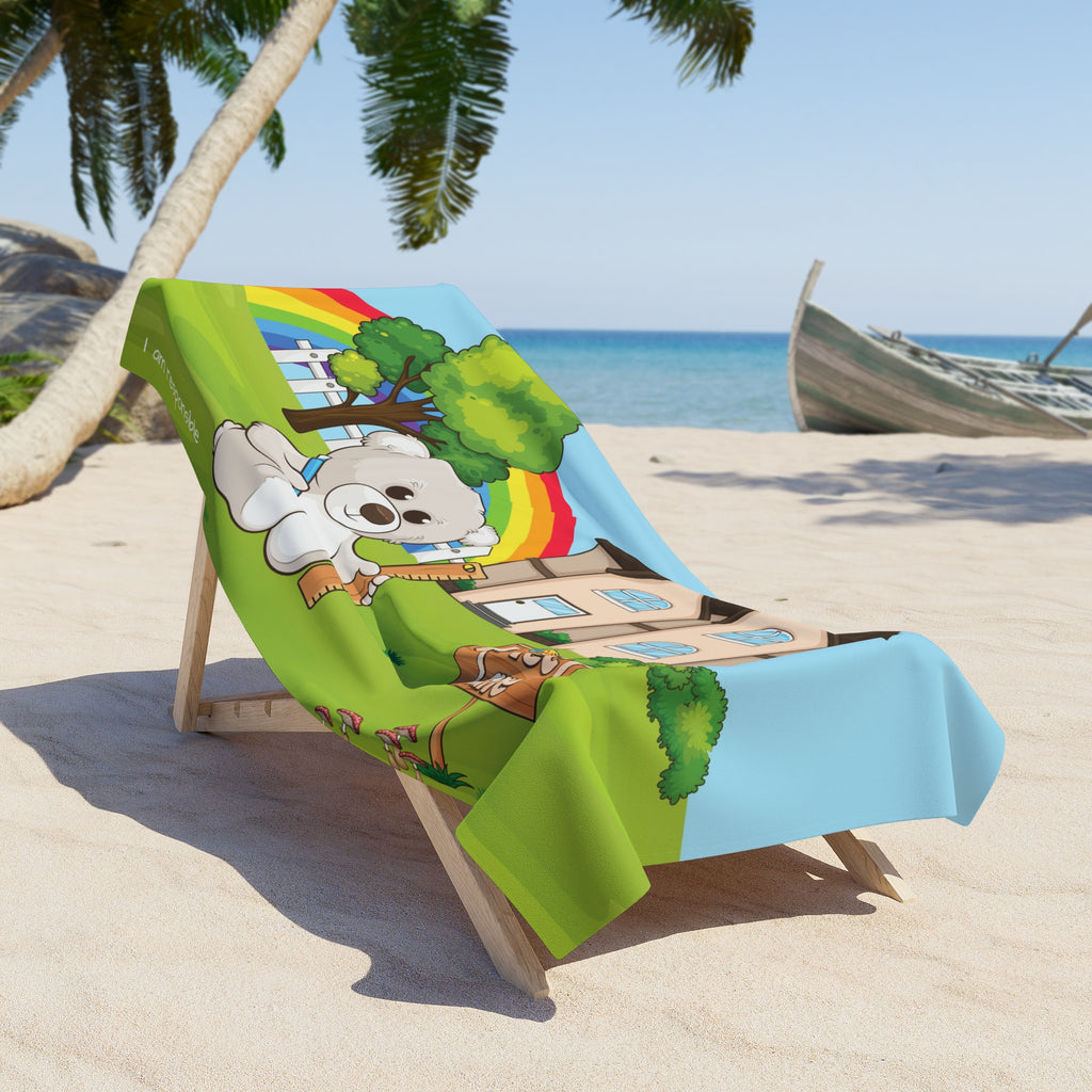 A 36 by 72 inch beach towel draped over a chair on a beach. The towel has a scene of a bear sitting in the yard of its house, a rainbow in the background, and the phrase "I am responsible" along the bottom.