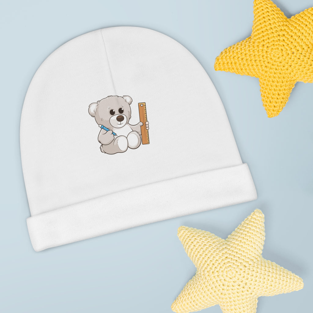 A white baby beanie with a small picture of a bear. The beanie has the bottom edge folded up.