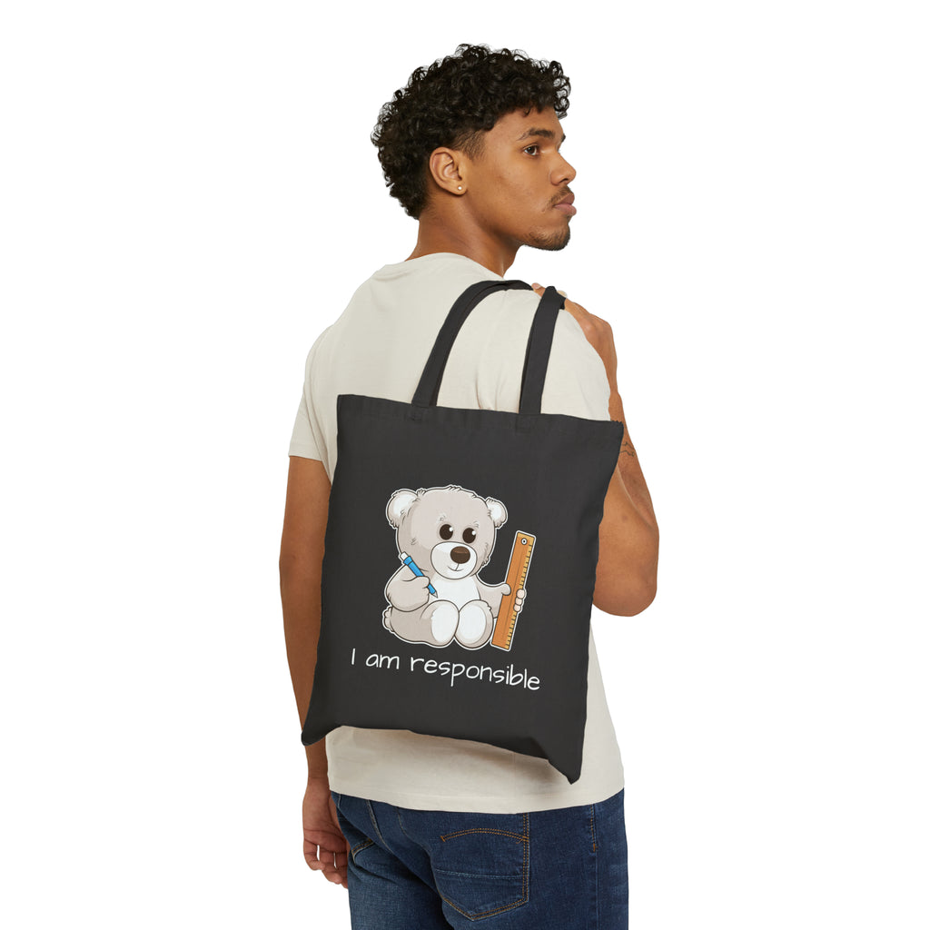 A man with a black tote bag over his shoulder, featuring a picture of a bear that says I am responsible.