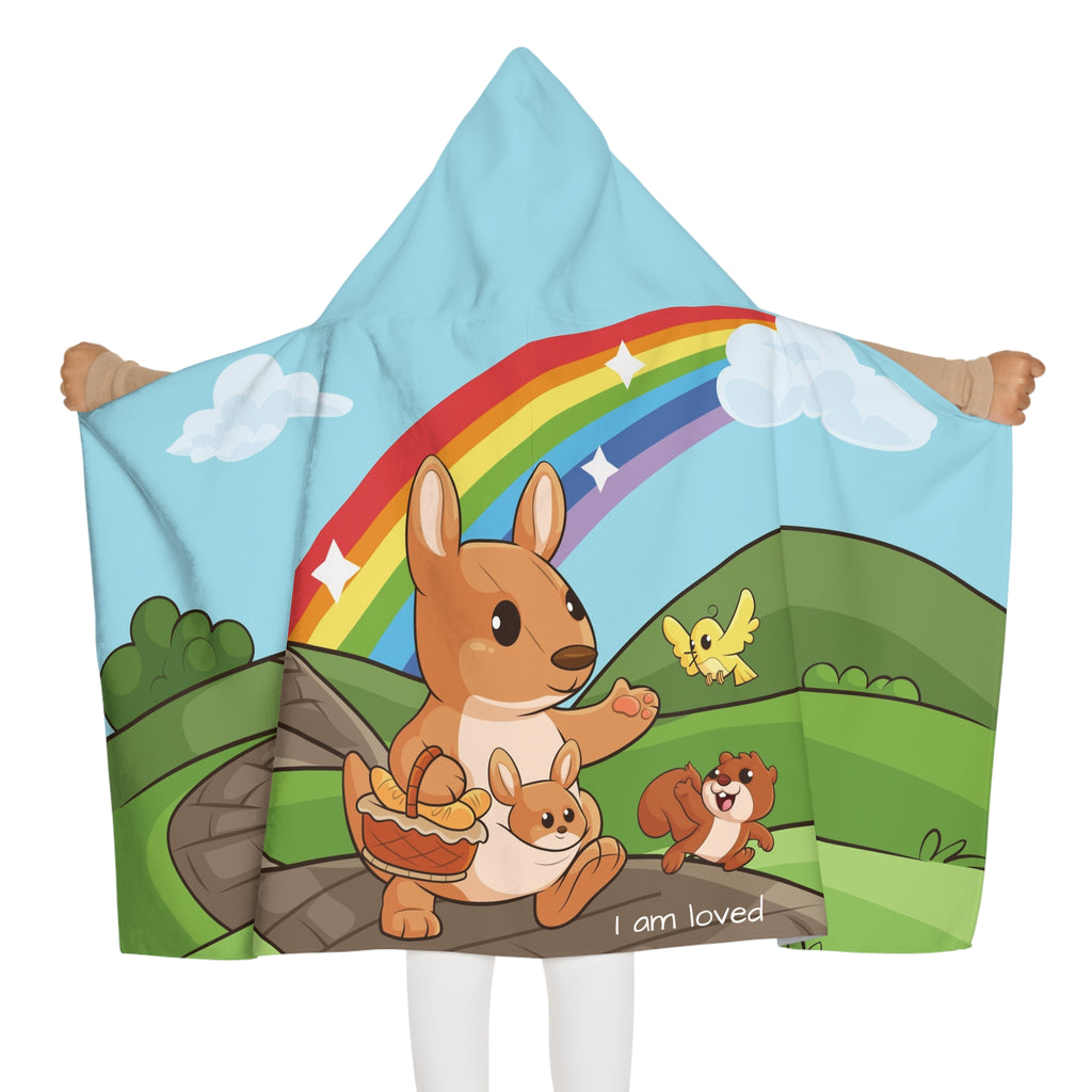 Back-view of a girl wearing a hooded towel and holding it open. The towel has a scene of a kangaroo walking along a path through rolling hills, a rainbow in the background, and the phrase "I am loved" along the bottom.