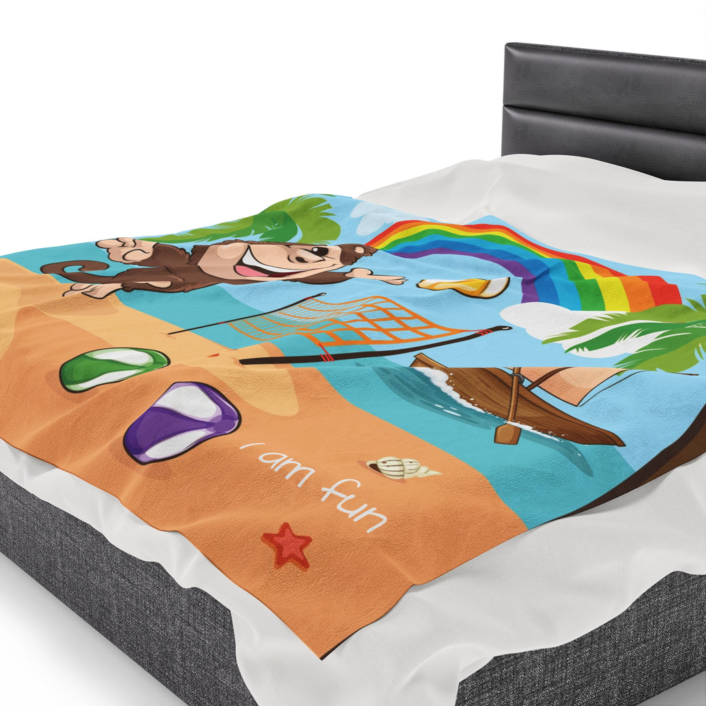 Side-view of a 60 by 80 inch blanket on a queen-sized bed. The blanket has a scene of a monkey playing volleyball on the beach, a rainbow in the background, and the phrase "I am fun" along the bottom.