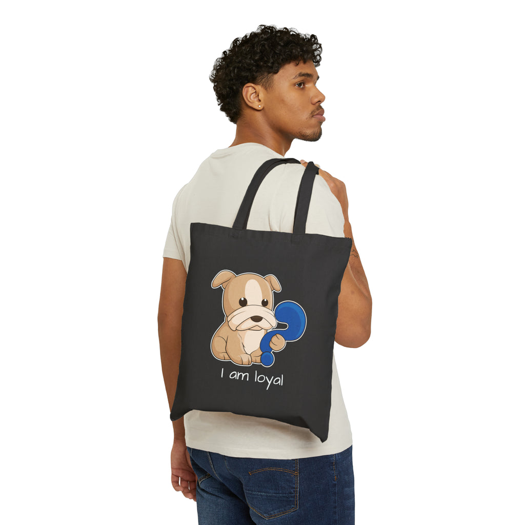 A man holding a black tote bag over his shoulder, featuring a picture of a dog that says I am loyal.