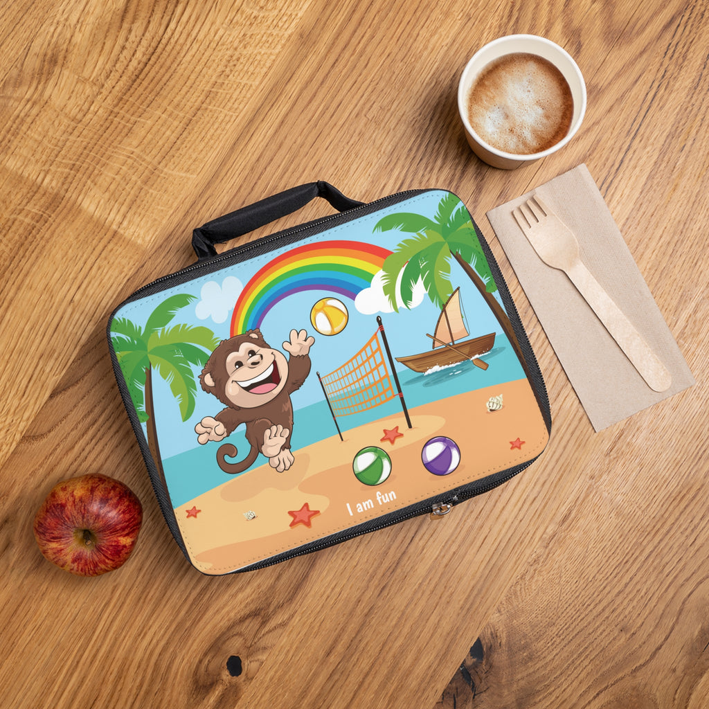A lunch bag laying closed on a table next to a cup, fork, and apple. The lunch bag has a scene on the front of a monkey playing volleyball on the beach, a rainbow in the background, and the phrase "I am fun" along the bottom.
