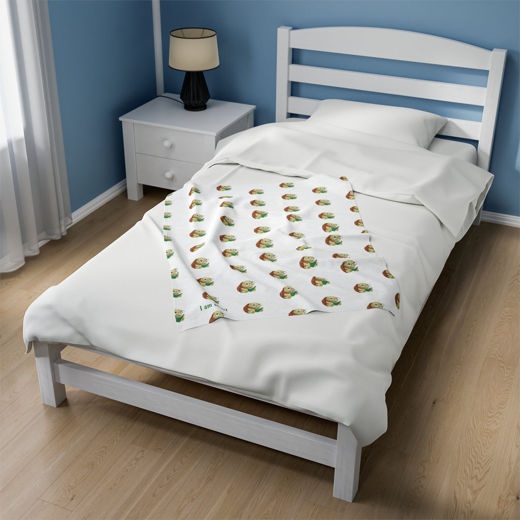 A 30 by 40 inch blanket on a twin-sized bed in a bedroom. The blanket has a repeating pattern of a turtle and the phrase “I am smart” in the bottom left corner.