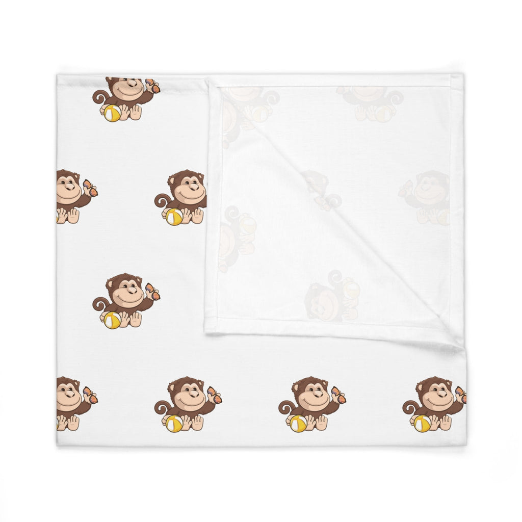 A white swaddle blanket with a repeating pattern of a monkey. The blanket is folded into a square.