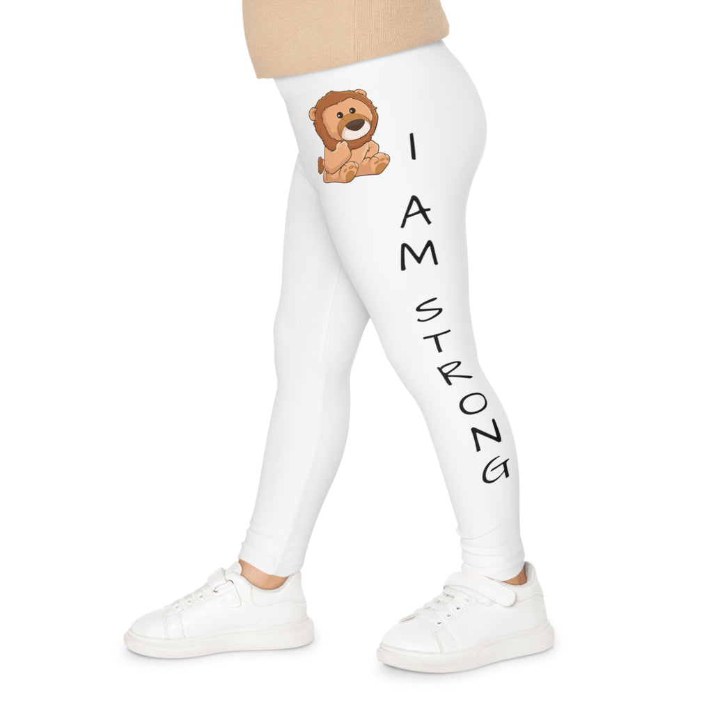 Left side-view of a child wearing white leggings with a picture of a lion on the front left waist and the phrase "I am strong" read top to bottom on the side of the leg.