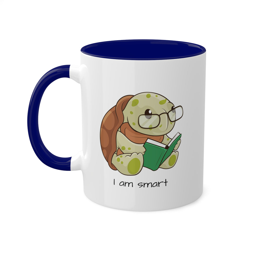 A white mug with a dark blue handle and interior and a picture of a turtle that says I am smart.