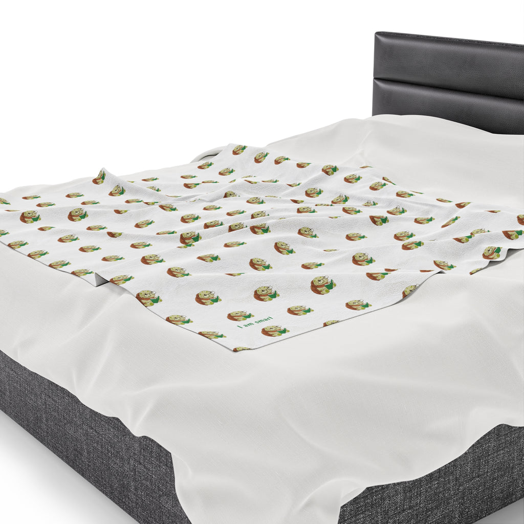 Side-view of a 50 by 60 inch blanket on a queen-sized bed. The blanket has a repeating pattern of a turtle and the phrase “I am smart” in the bottom left corner.
