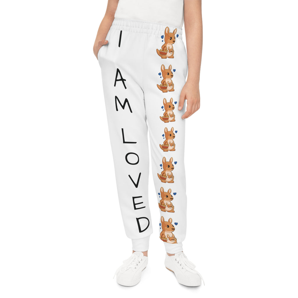 Front-view of a girl wearing white sweatpants with a line of kangaroos down the front left leg and the phrase "I am loved" down the front right leg.