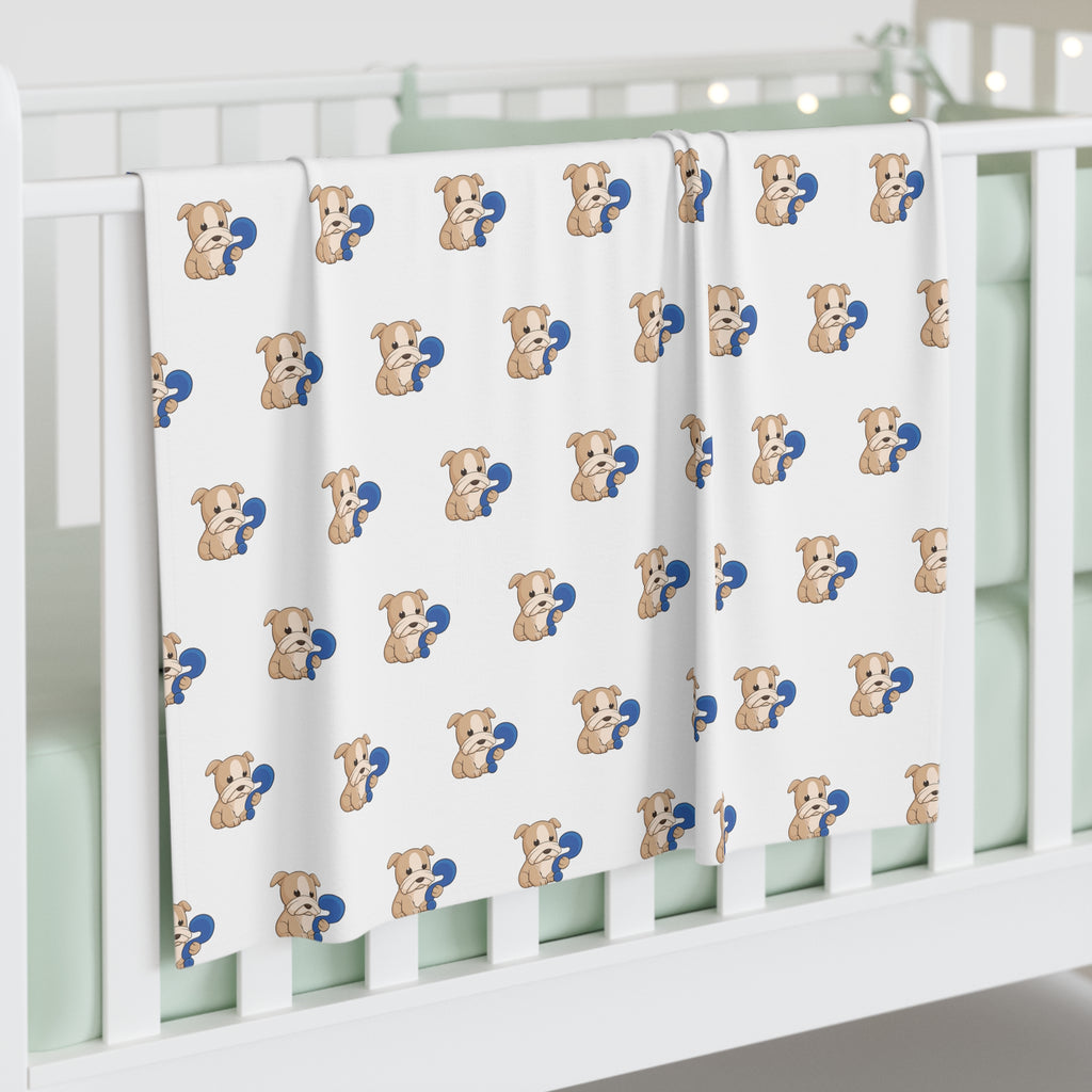 A white swaddle blanket with a repeating pattern of a dog. The blanket is draped over the side of a baby crib.