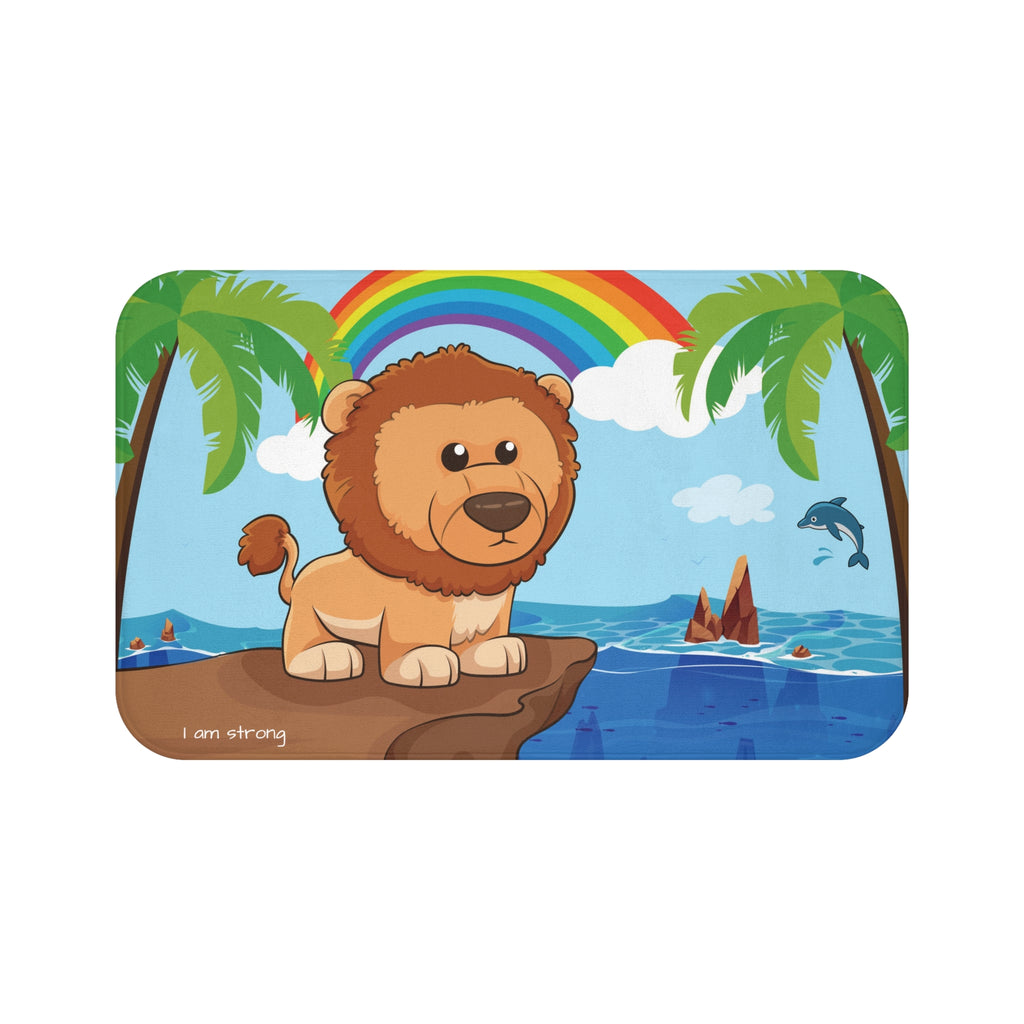 A 34 by 21 inch bath mat that has a scene of a lion standing on a cliff over the ocean with a rainbow in the background and the phrase "I am strong" along the bottom.