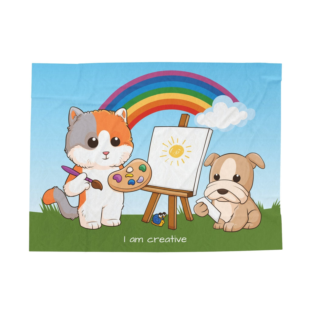 A blanket that has a scene of a cat painting on a canvas next to a dog, a rainbow in the background, and the phrase "I am creative" along the bottom.