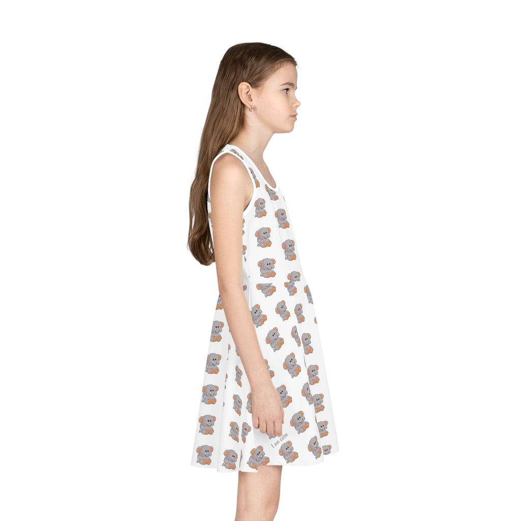 Right side-view of a girl wearing a sleeveless white dress with a repeating pattern of an elephant.