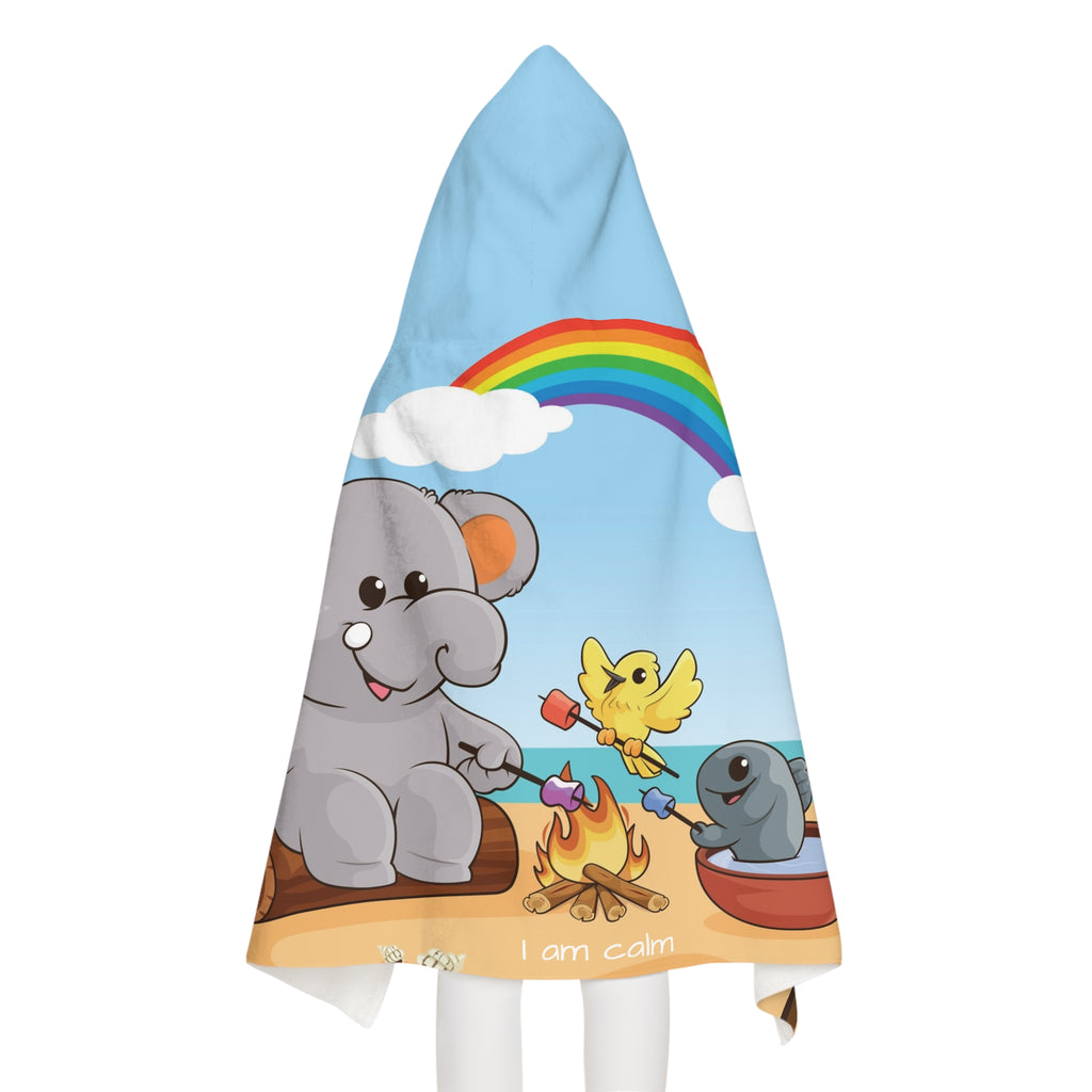Back-view of a girl wearing a hooded towel. The towel has a scene of an elephant having a bonfire with a bird and fish on the beach, a rainbow in the background, and the phrase "I am calm" along the bottom.