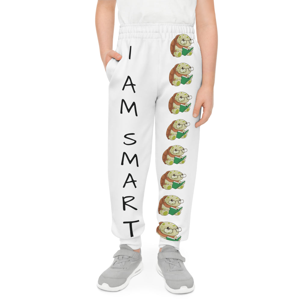 Front-view of a boy wearing white sweatpants with a line of turtles down the front left leg and the phrase "I am smart" down the front right leg.