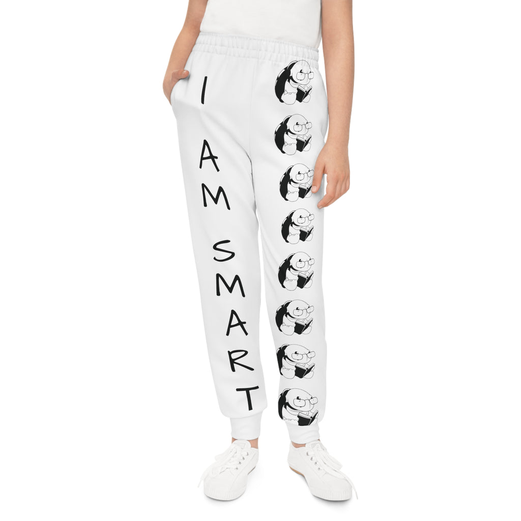 Front-view of a girl wearing white sweatpants with a line of black and white turtles down the front left leg and the phrase "I am smart" down the front right leg.