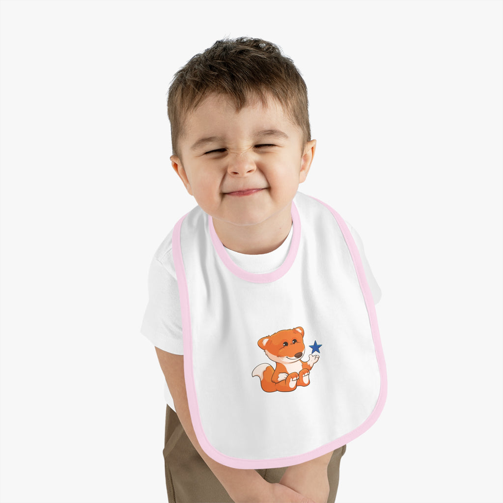 A little boy wearing a white baby bib with light pink trim and a small picture of a fox.