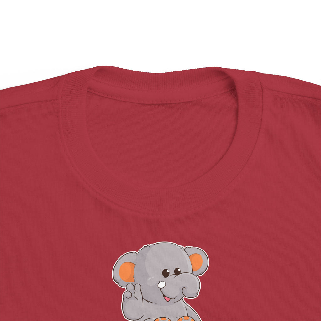 A close-up of the crew neckline of a short-sleeve garnet red shirt with a picture of an elephant that says Peace.