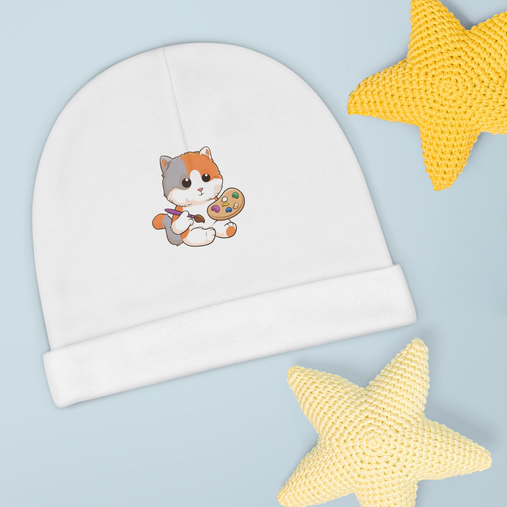A white baby beanie with a small picture of a cat. The beanie has the bottom edge folded up.