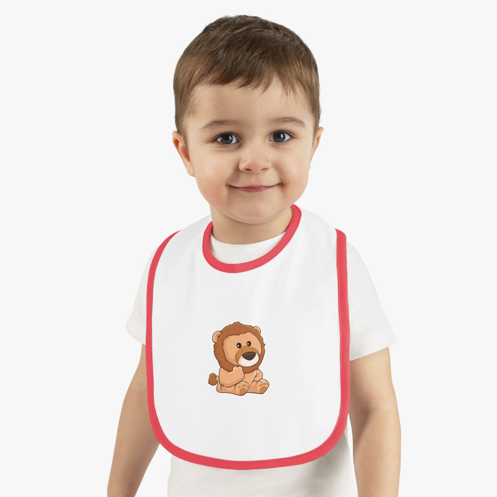 A little boy wearing a white baby bib with red trim and a small picture of a lion.