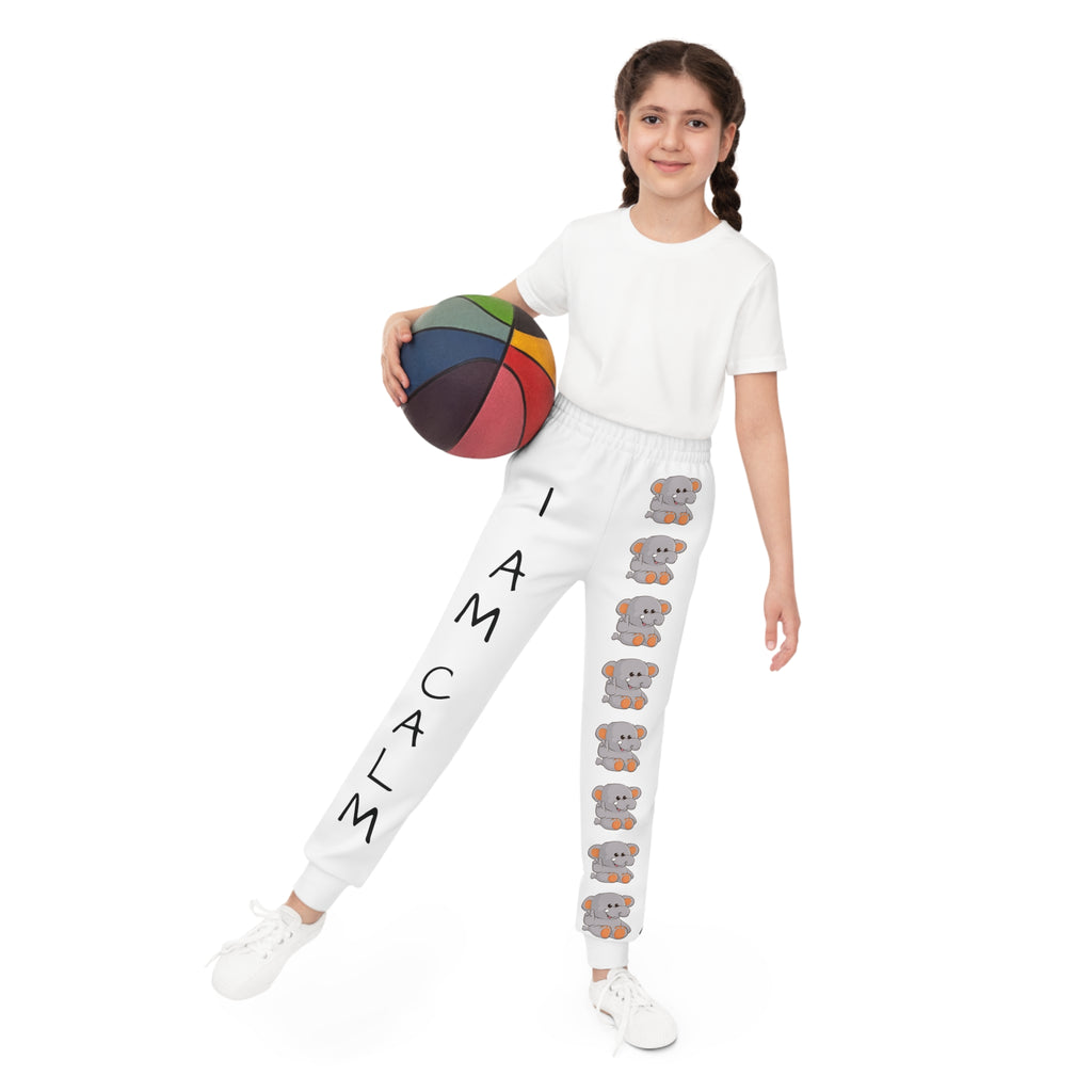 Front-view of a girl holding a basketball and wearing white sweatpants. The pants have a line of elephants down the front left leg and the phrase "I am calm" down the front right leg.