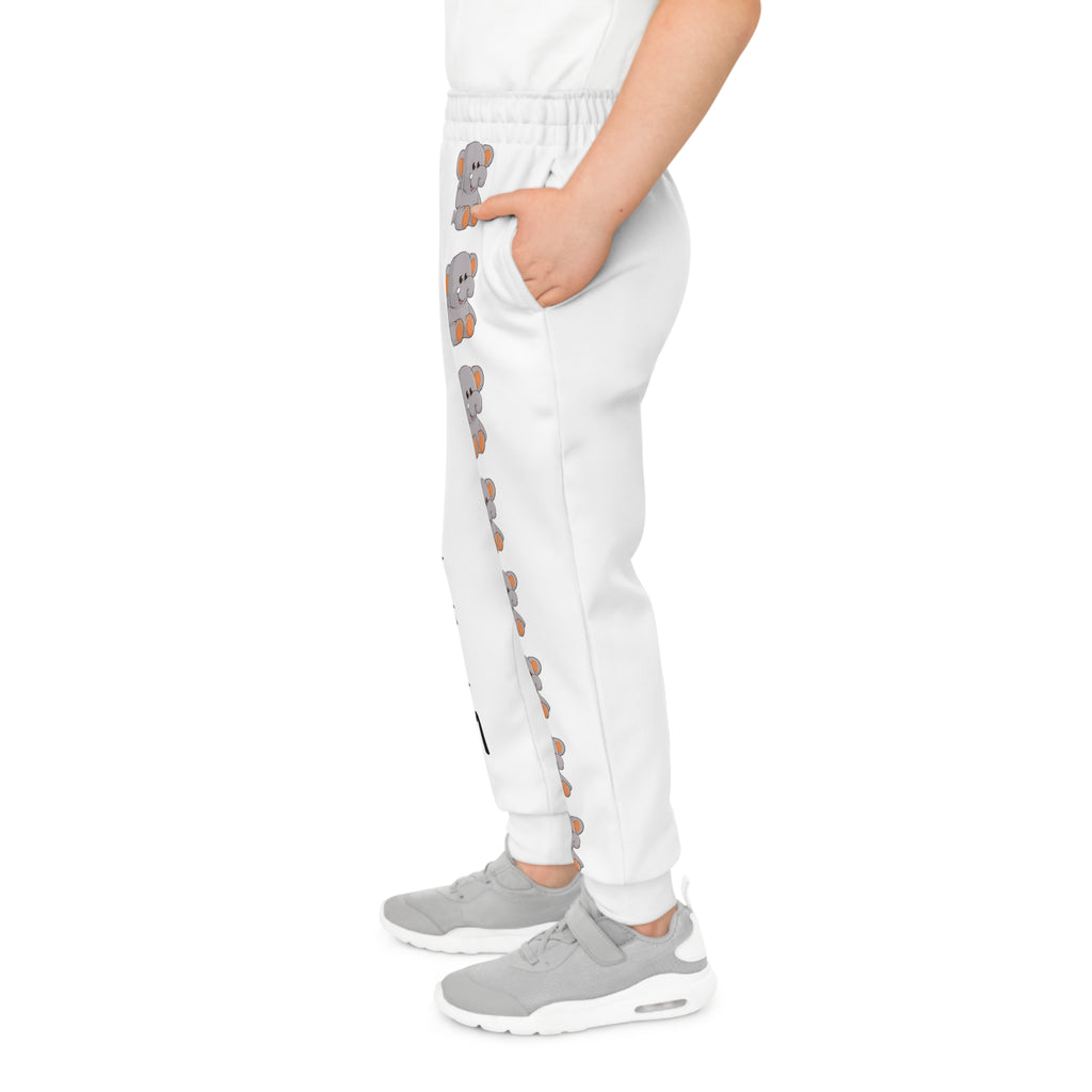 Left side-view of a boy wearing white sweatpants with a line of elephants down the front left leg.