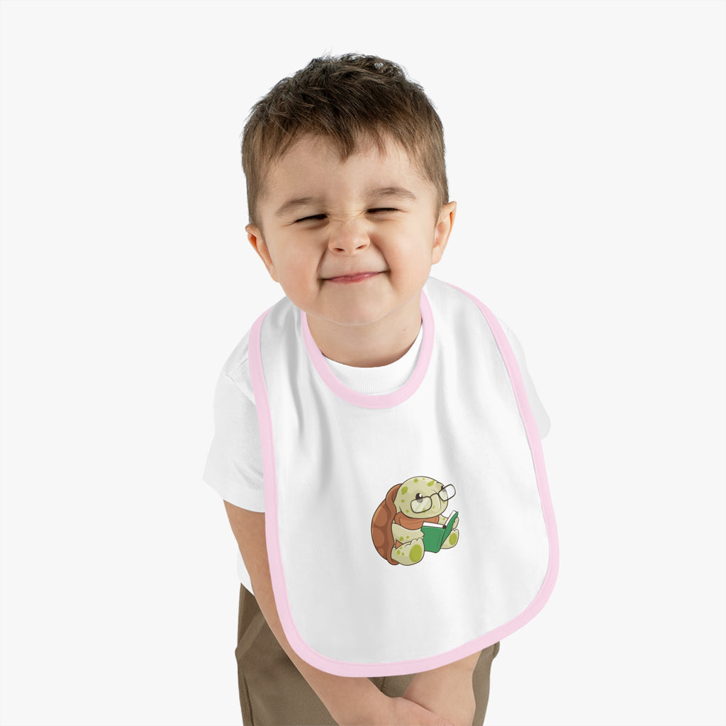A little boy wearing a white baby bib with light pink trim and a small picture of a turtle.