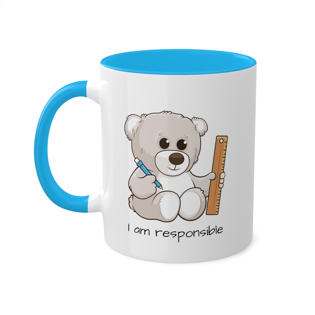 A white mug with a light blue handle and interior and a picture of a bear that says I am responsible.