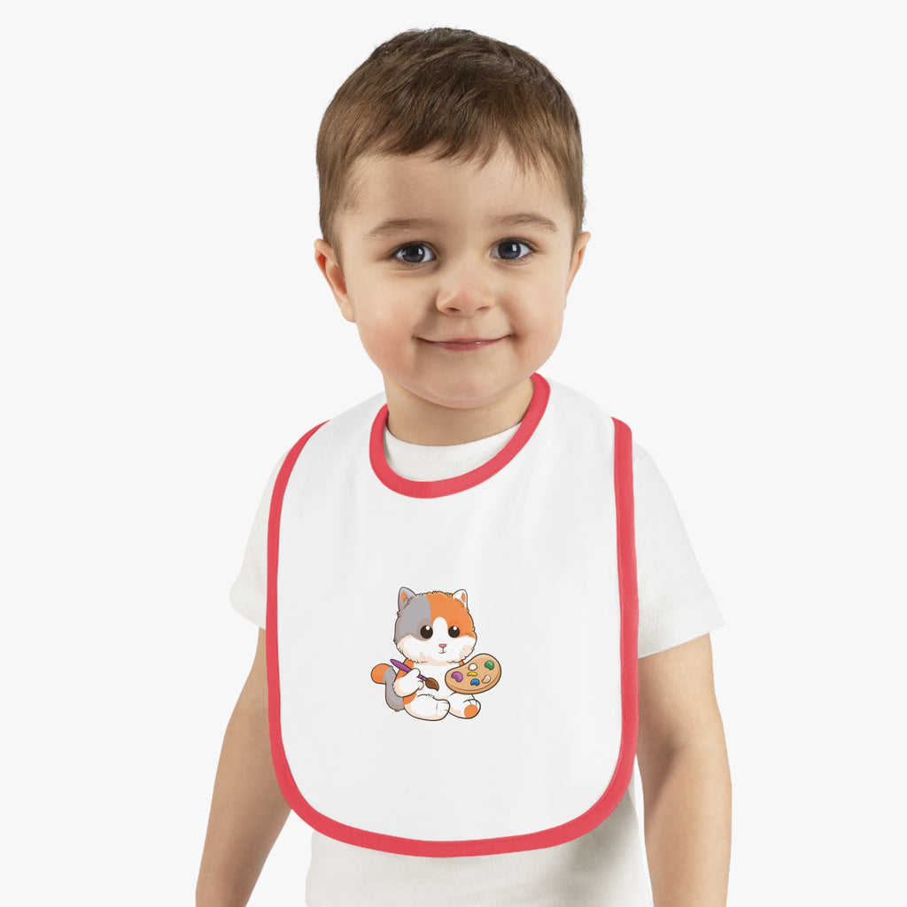 A little boy wearing a white baby bib with red trim and a small picture of a cat.
