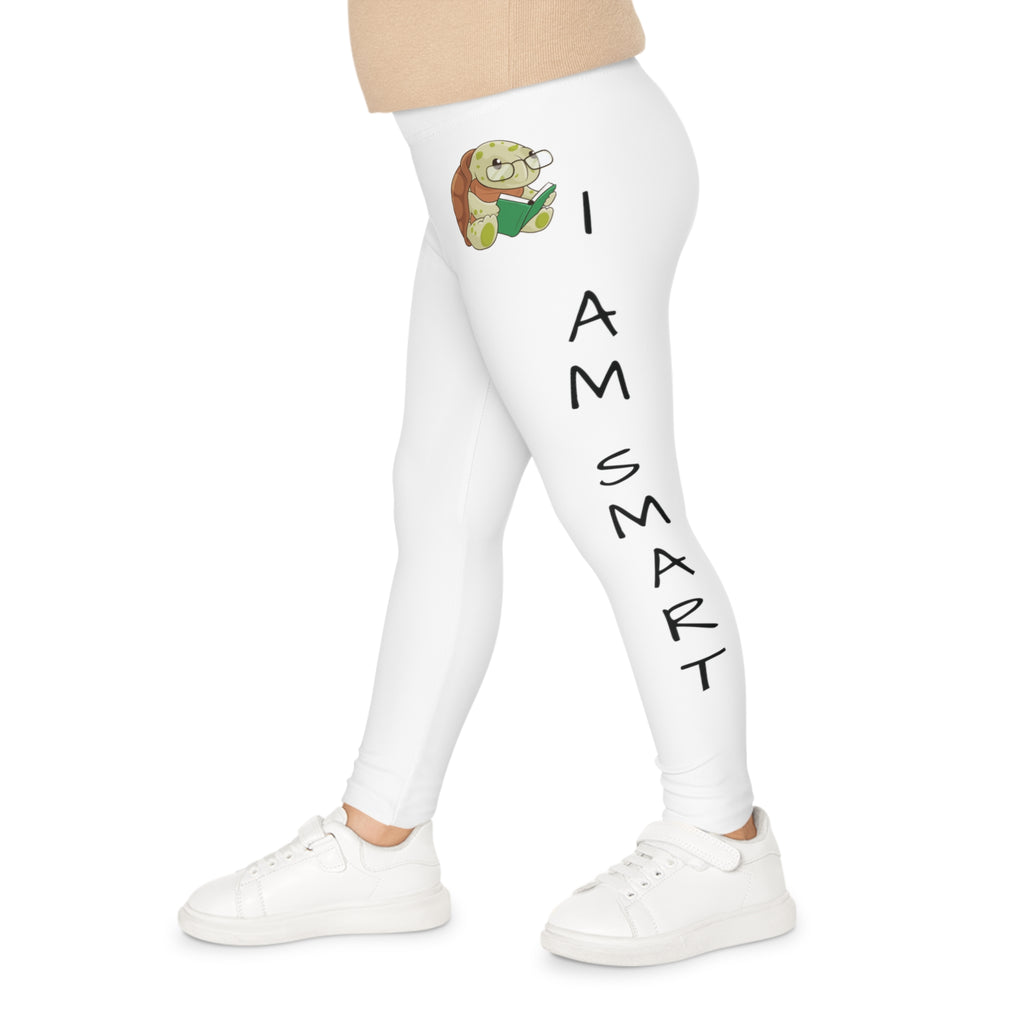 Left side-view of a child wearing white leggings with a picture of a turtle on the front left waist and the phrase "I am smart" read top to bottom on the side of the leg.
