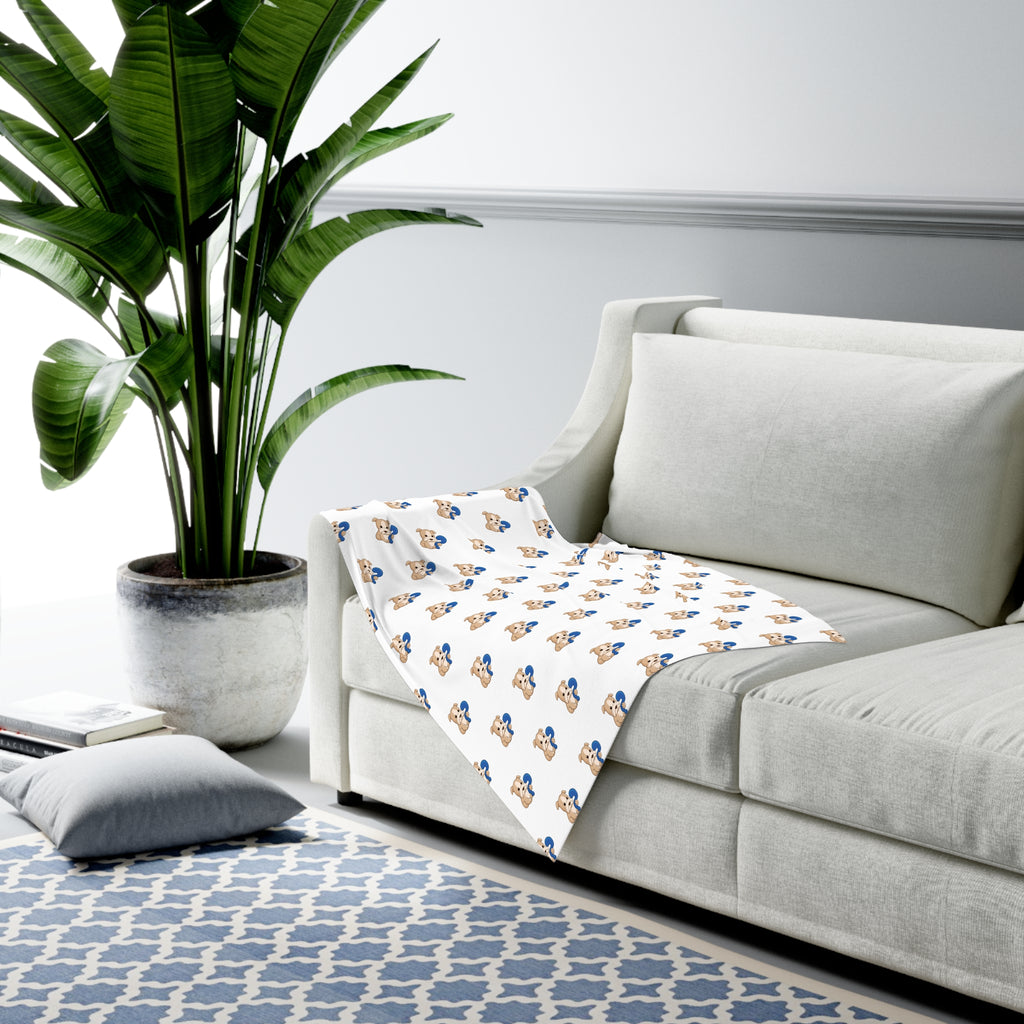 A white swaddle blanket with a repeating pattern of a dog. The blanket is draped over the armrest of a couch.