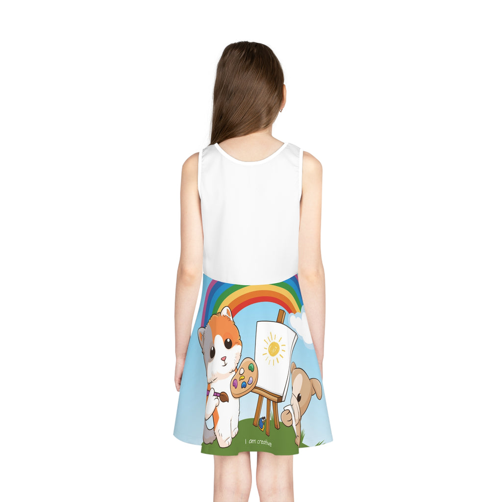 Back-view of a girl wearing a sleeveless dress. The dress has a white top and the skirt features a scene of a cat painting on a canvas next to a dog and the phrase "I am creative" along the bottom.