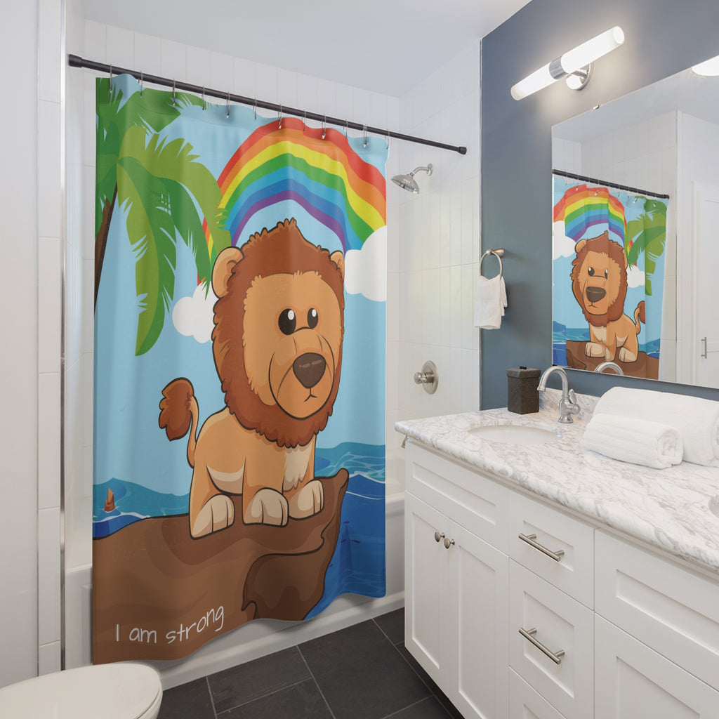 A shower curtain hanging from a rod in front of a built-in tub in a bathroom. The shower curtain has a scene of a lion standing on a cliff over the ocean with a rainbow in the background and the phrase "I am strong" along the bottom.