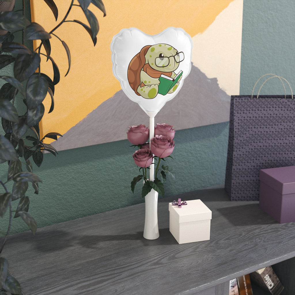 A heart-shaped white mylar balloon on a stick with a picture of a turtle. The balloon sits in a flower vase on a gift table.