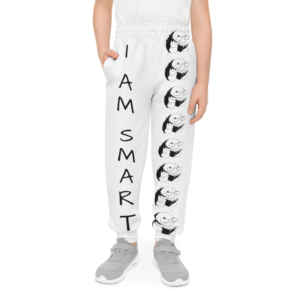 Front-view of a boy wearing white sweatpants with a line of black and white turtles down the front left leg and the phrase "I am smart" down the front right leg.