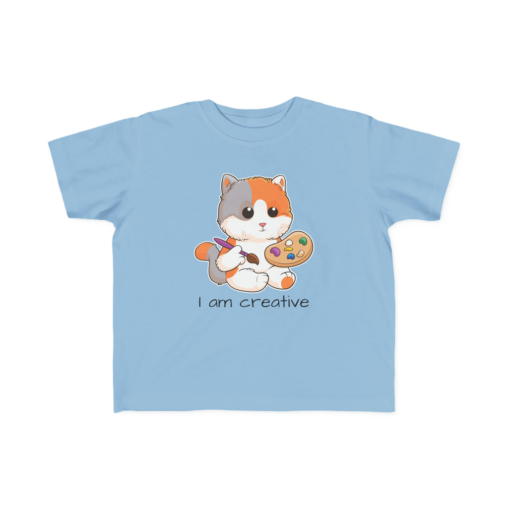 A short-sleeve light blue shirt with a picture of a cat that says I am creative.