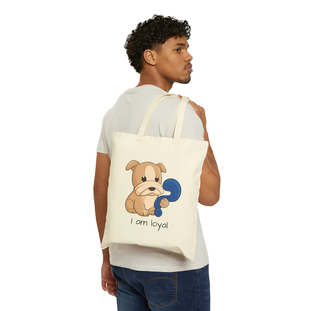 A man with a natural tan tote bag over his shoulder, featuring a picture of a dog that says I am loyal.