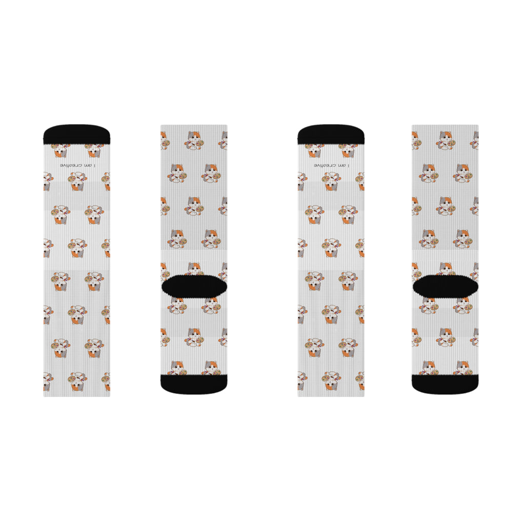 A pair of socks, showing the top and bottom of both. The crew-length socks are white with black toes and heels and a repeating pattern of a cat.