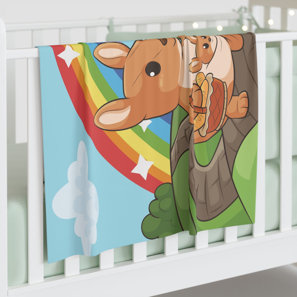 Full-color swaddle blanket with a kangaroo walking along a path through rolling hills with a rainbow in the background. The blanket is draped over the side of a baby crib.