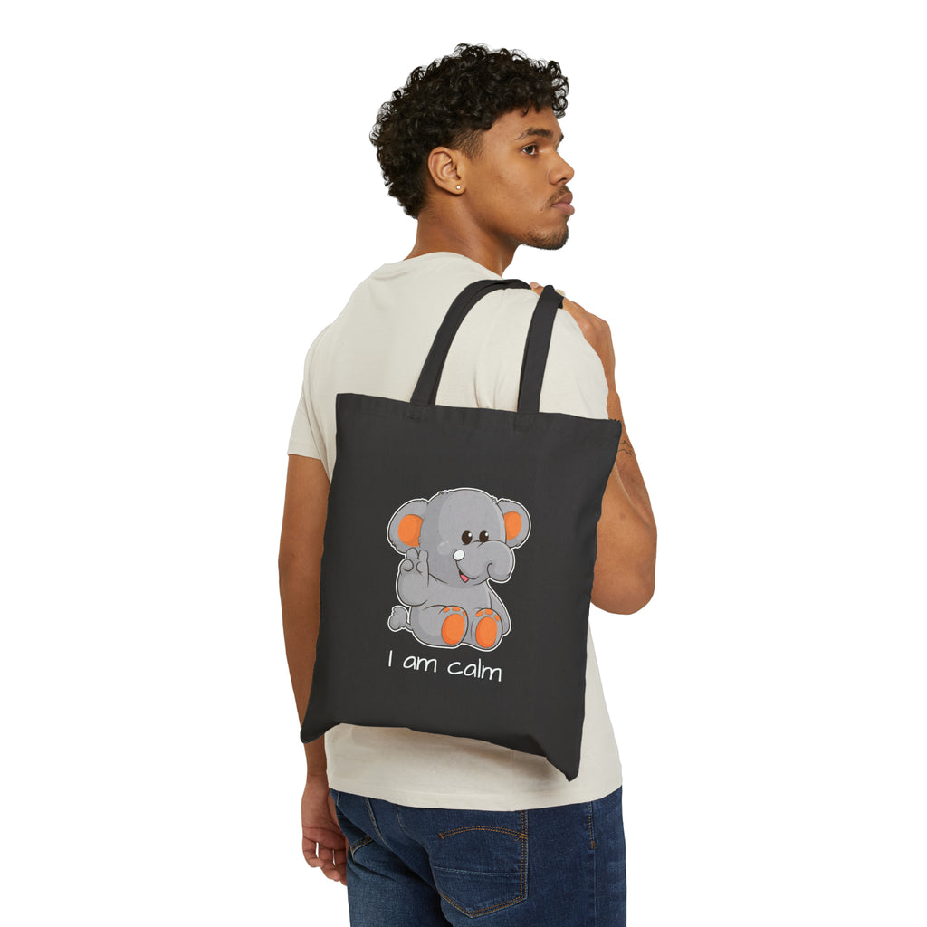 A man with a black tote bag over his shoulder, featuring a picture of an elephant that says I am calm.