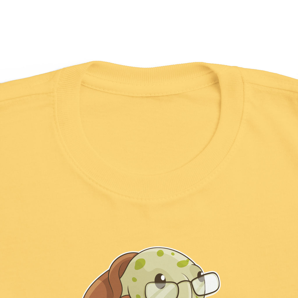 A close-up of the crew neckline of a short-sleeve yellow shirt with a picture of a turtle that says I am smart.